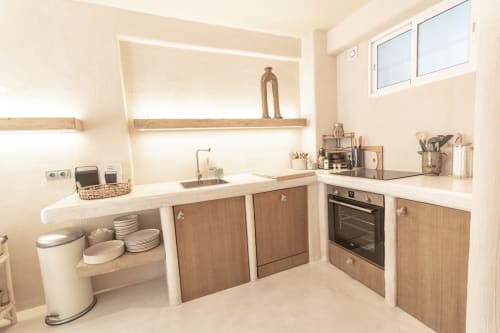 Modern kitchenette at Escanda Building Solutions hotel with wooden cabinets, white countertops, built-in oven, and organized