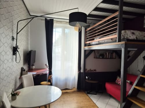 Studio Les Caudalies à Orval Et Sens, Orvault : loft moderne avec lit mezzanine, table ronde, lampadaire noir et vue sur la ville
