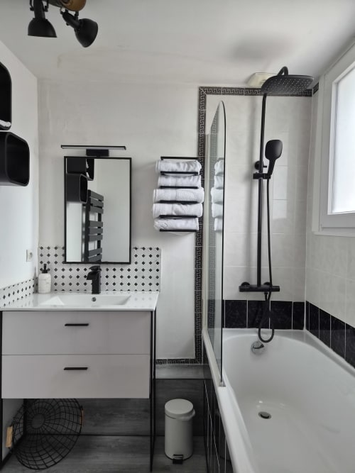 Salle de bain moderne Orval Et Sens : vasque blanche, carrelage géométrique noir, pomme de douche pluie et serviettes blanches à Orvault