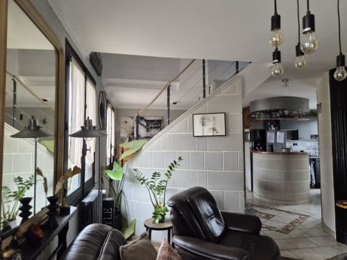 Salon moderne d'un duplex à Orvault avec sièges en cuir noir, éclairage suspendu et accès escalier chez Orval Et
