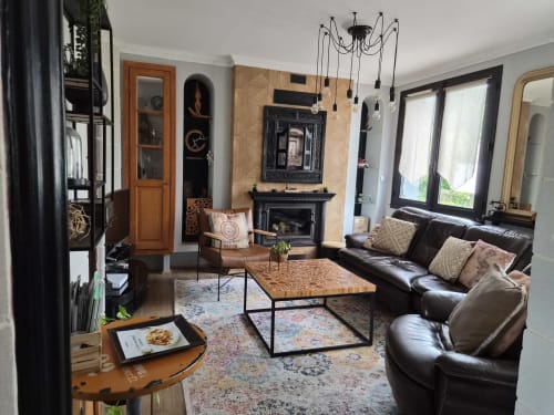 Séjour moderne de l'appartement Orval Et Sens avec canapé cuir noir, cheminée, luminaires suspendus et portes-fenêtres à Orvault