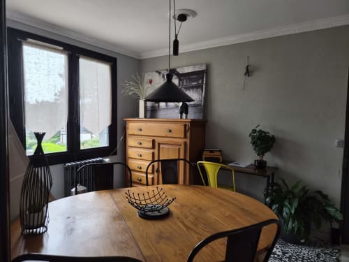 Salle à manger contemporaine dans le duplex Orval Et Sens, avec table en bois, suspension noire et vue sur la ville par grandes fenêtres