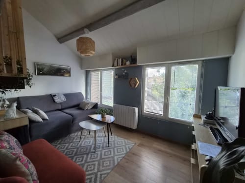 Salon moderne de l'appartement L'Absolu à Orval Et Sens, Orvault, avec canapé bleu marine, tapis à motifs et grandes fenêtres