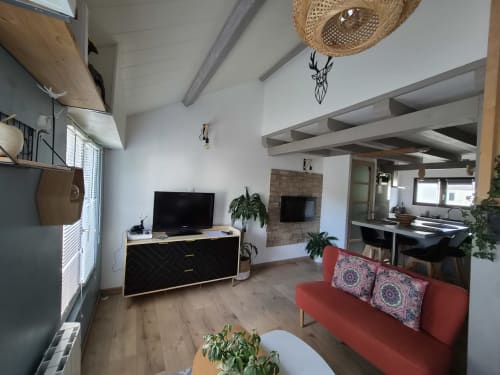 Séjour ouvert moderne de l'appartement Orval Et Sens avec canapé rouge, téléviseur, cuisine et cheminée à Orvault