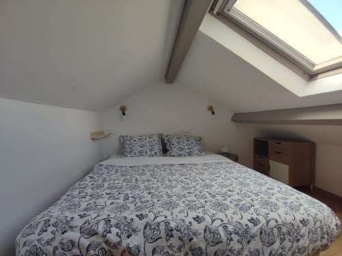 Chambre lumineuse sous les toits avec puits de lumière, couette à motifs, mobilier en bois et plafonds mansardés à l'hôtel Orval Et Sens à Orvault