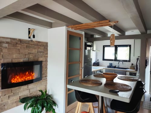 Salle à manger moderne avec foyer électrique, poutres en bois, cuisine et table à manger à Orval Et Sens à Orvault