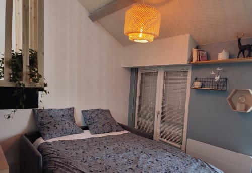 Chambre moderne de l'appartement Orval Et Sens à Orvault avec literie à motifs bleus, lampe suspendue, étagères et placards