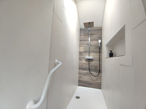 Salle de bain moderne avec carrelage imitation bois et sanitaires blancs à l'hôtel Orval Et Sens à Orvault