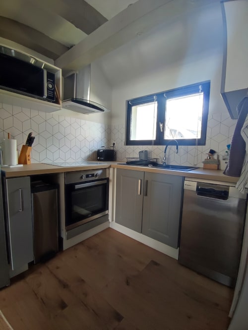 Cuisine moderne de l'appartement L'Absolu à Orval Et Sens, Orvault, avec électroménagers inox et fenêtres à cadres bleus