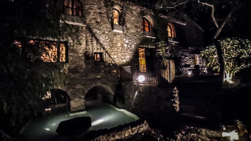 Historic stone building at night with illuminated windows, arched passages, and courtyard pool at Escanda Building Solutions