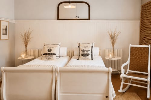 Dos camas gemelas con marcos blancos en un dormitorio luminoso de la casa rural Casa Celso en Baiona, España, con decoración vintage