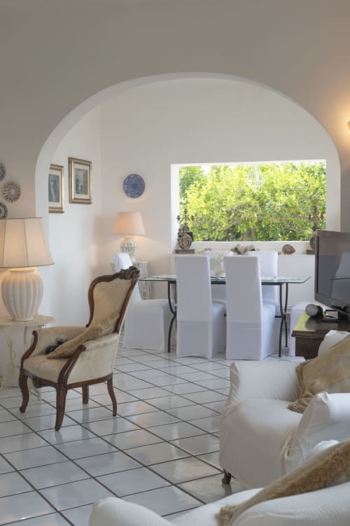 Elegante salotto a La Capperina, Capri con soffitti voltati, arredamenti bianchi e viste sui giardini mediterranei