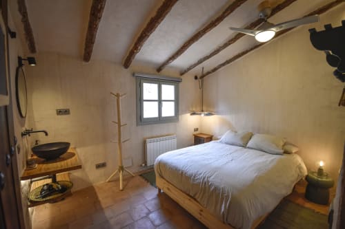 Rustic hotel bedroom with exposed wooden beams, modern amenities, and ensuite bathroom at Escanda Building Solutions, Spain