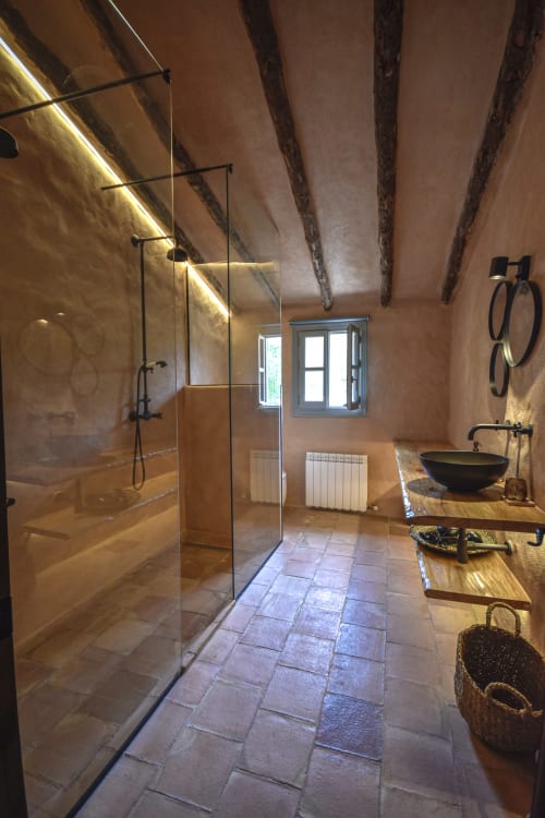 Rustic bathroom with glass shower, wooden beams, terracotta walls, and black vessel sink at Escanda hotel