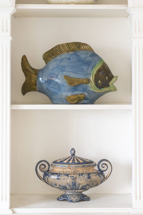Scultura decorativa di pesce e vaso blu ornato esposti su scaffali bianchi a La Capperina, Capri