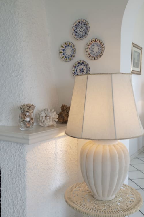 Elegante lampada con paralume plissettato su base decorativa accanto a mensola con piatti in ceramica blu e bianca a La Capperina, Capri