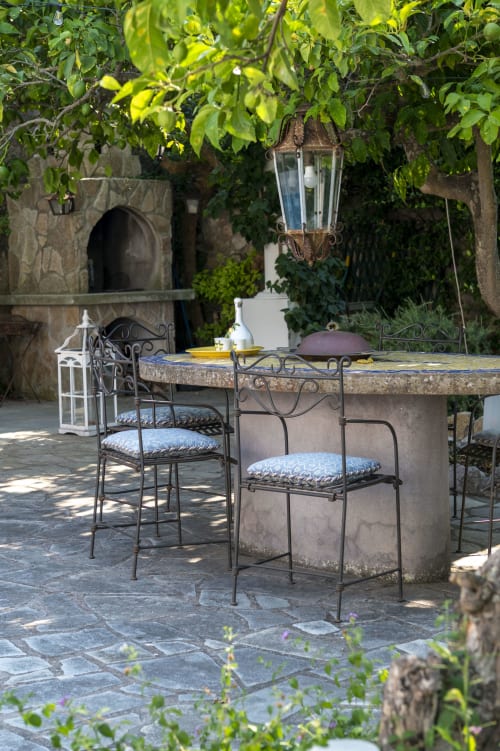 Terrazza all'aperto di La Capperina a Capri, con sedute in ferro battuto e rigogliosa vegetazione overhead