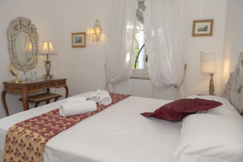 Camera elegante dell'hotel La Capperina a Capri con biancheria bianca, accenti burgundy e arredi classici