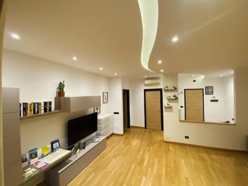 Soggiorno moderno presso MiSaNi Apartments a Novara con pavimenti in legno, mobile TV e design contemporaneo del soffitto