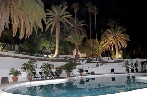Piscina del hotel Cortijo San Ignacio por la noche con palmeras, tumbonas y arquitectura blanca en terrazas en El Cortijo, España