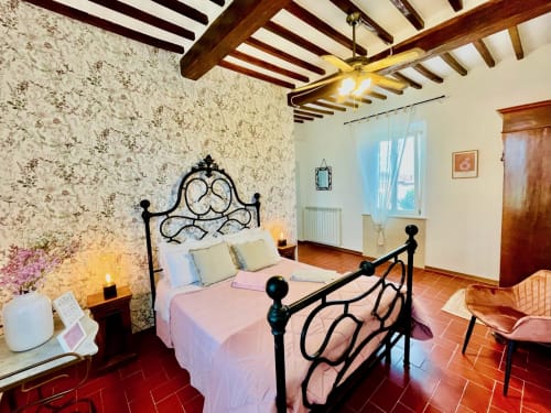 Camera Il Profumo presso Agriturismo CasaViVa con letto in ferro battuto, travi a vista e vista sul giardino a Pozzo della Chiana