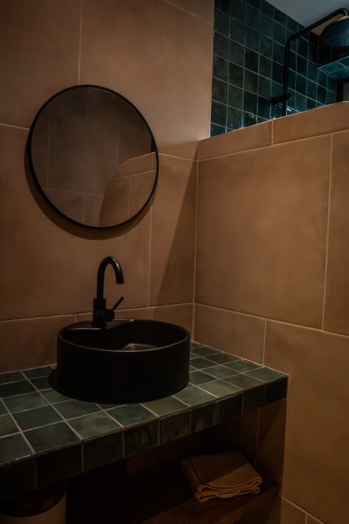 Salle de bain moderne à L'Étape du Pellerin, Maison Antea B&B : lavabo noir rond, miroir circulaire, carrelage beige