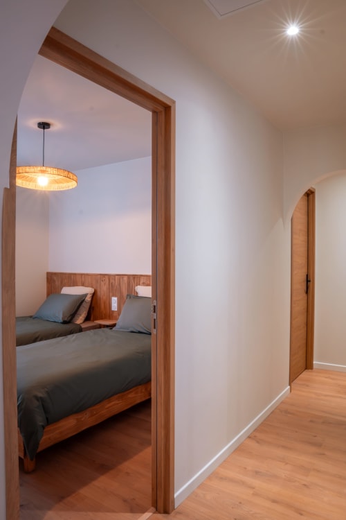 Chambre L'Étape du Pellerin de la Maison Antea B&B au Puy-en-Velay avec lit en bois et luminaire suspendu