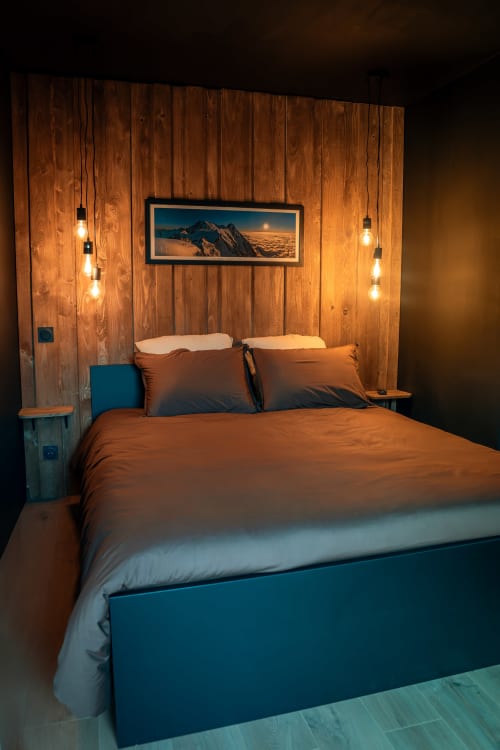 Chambre douillette à la Maison Antea Le Refuge au Puy-en-Velay avec murs en bois, luminaires suspendus et œuvres d'art paysagères montagnards