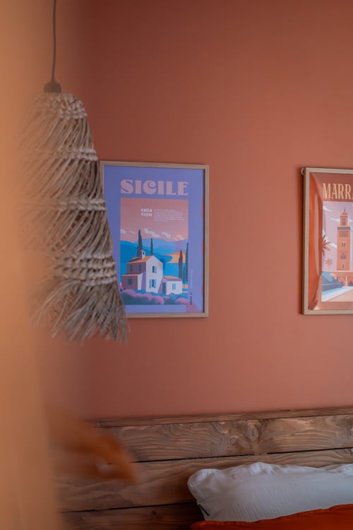 Chambre aux tons terre cuite chaleureuse à la Maison Antea B&B avec affiches de voyage et lampe suspendue tissée au-dessus du lit en bois