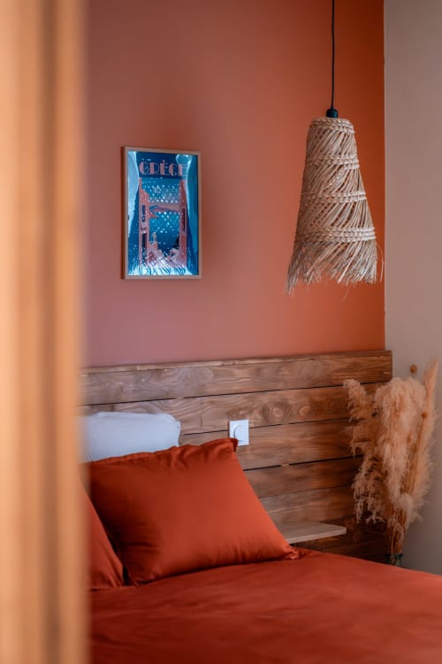 Chambre accueillante à la Maison Antea B&B au Puy-en-Velay avec murs en terre cuite, lit en bois, linge de lit orange et luminaire en osier tressé