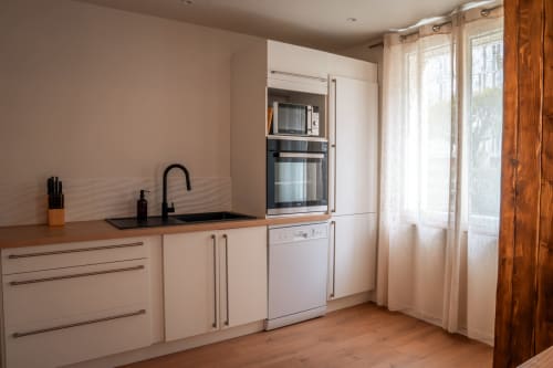 Cuisine moderne au gîte Maison Antea du Puy-en-Velay : mobilier blanc, évier noir et parquet