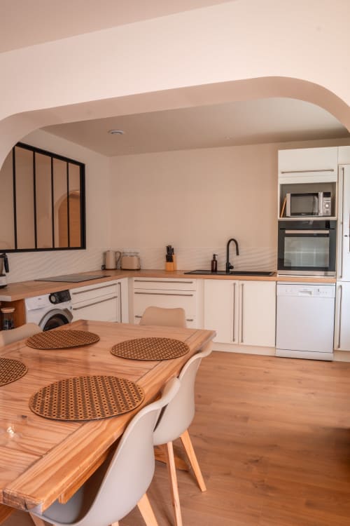 Cuisine-salle à manger contemporaine du gîte Maison Antea au Puy-en-Velay avec table en bois, mobilier blanc et électroménager inox