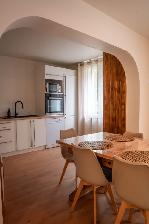 Cuisine-séjour moderne de la Maison Antea au Puy-en-Velay avec table en bois, voûte cintrée et design contemporain