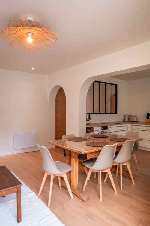 Élégante salle à manger de la Maison Antea B&B au Puy-en-Velay avec table en bois, chaises blanches et luminaire tressé au plafond