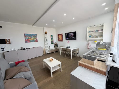 Modern luxury apartment in Como, Italy with open-plan living area, kitchen, dining space, and sofa with ocean and mountain
