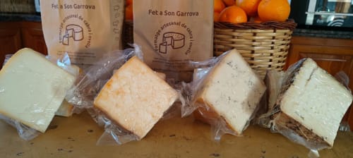 Fromages artisanaux de Fét a Son Garrova présentés à l'Agroturismo Ses Illes à Costitx avec des oranges en arrière-plan