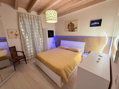 Modern bedroom at Versilia Panoramic Luxury in Como, Tuscany, featuring yellow bedding and ambient blue lighting