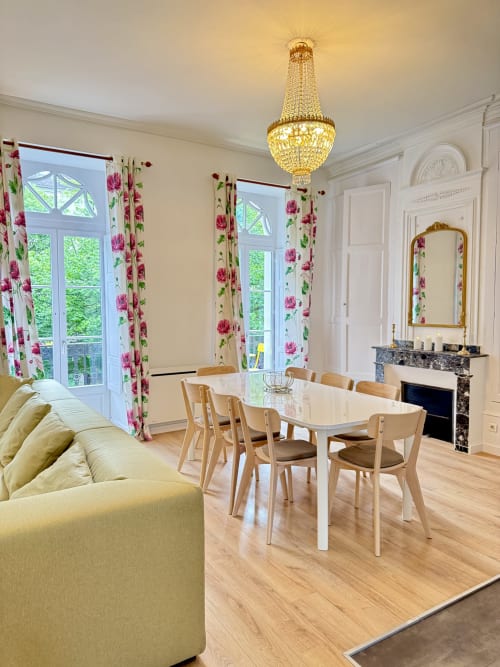 Elegant dining room with crystal chandelier, floral curtains, and mountain views at Les meublés d'Étigny apartment,