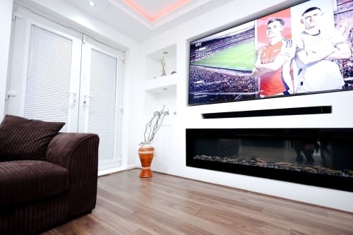 Modern living room with burgundy sofa, fireplace, wall-mounted TV, and city view in Salford apartment