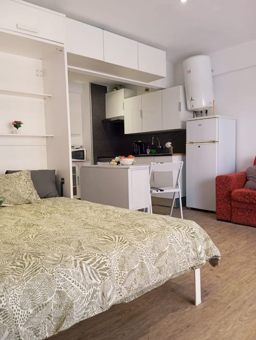 Quarto de estúdio com kitchenette, cama queen, sofá vermelho, móveis brancos e comodidades modernas no hotel de Portimão
