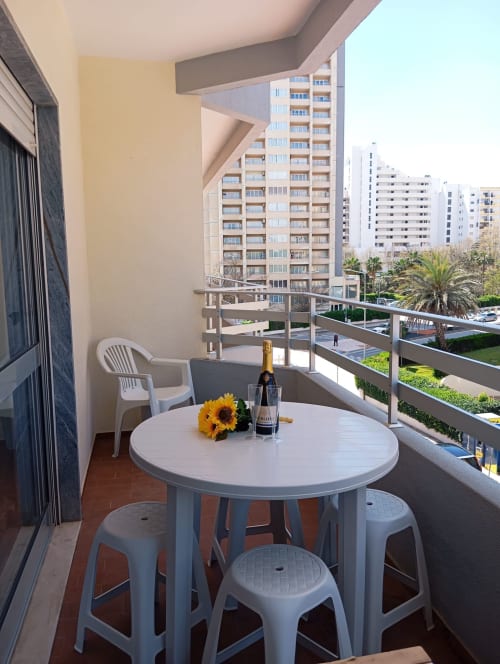 Varanda do apartamento Sweet Home Casa dos Arcos em Portimão com mesa redonda, cadeiras, girassóis e vista para a cidade
