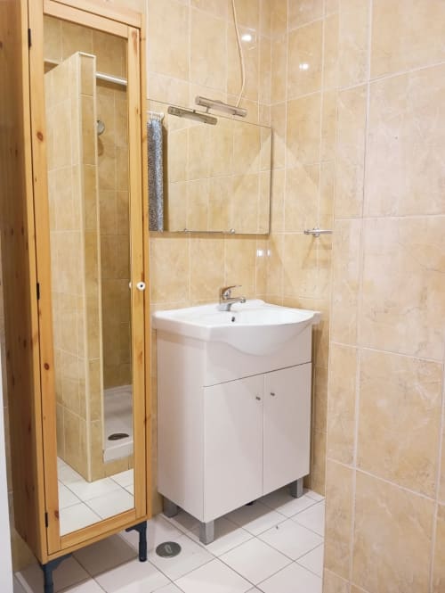 Banheiro moderno com pia branca, espelho grande e chuveiro com divisória de vidro no apartamento Sweet Home Casa dos Arcos