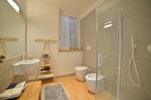 Bagno moderno dell'hotel Proprietà Clara ad Assisi con doccia walk-in, bidet e dettagli in legno