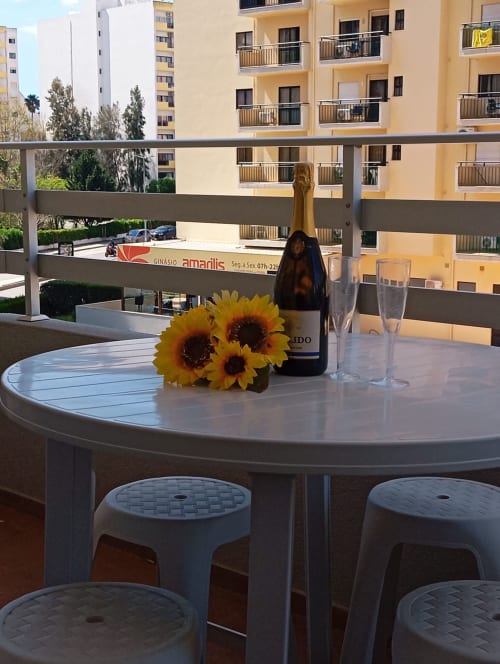 Mesa de varanda com girassóis e garrafa de champanhe com vista para os edifícios de Portimão