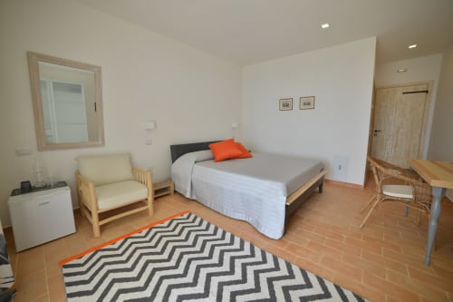 Camera luminosa della Proprietà Clara ad Assisi con letto matrimoniale, mobili in legno e tappeto con motivi geometrici