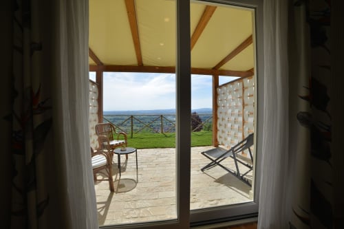 Vista dalla Villa Clara B&B di Assisi attraverso le porte aperte verso il patio del giardino con paesaggio circostante