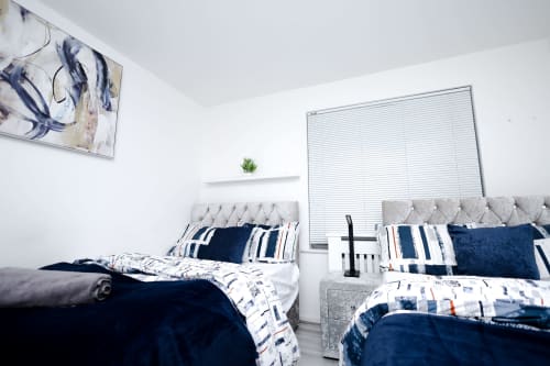 Modern bedroom in Salford apartment with twin beds, grey headboards, navy and white bedding, and white walls
