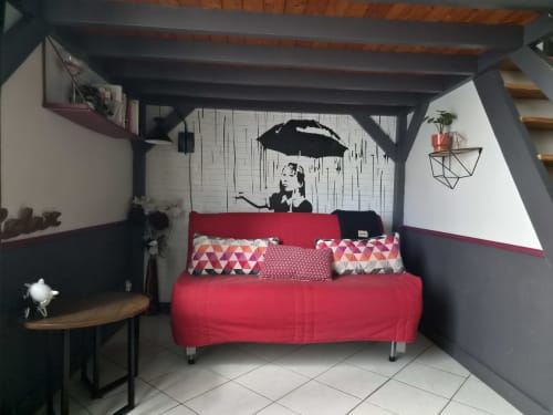 Canapé rouge avec coussins géométriques dans la chambre loft moderne de l'hôtel Orval Et Sens à Orvault, avec un mur de parapluies artistiques