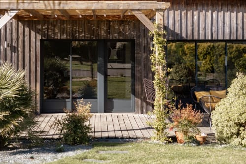Modern wooden cottage with glass doors, pergola, and landscaped garden at Manoir de la Nogrie, Val d'Izé