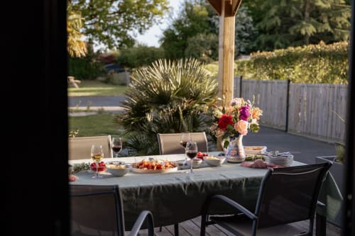 Outdoor dining setup on private wooden terrace with flowers, wine glasses, and garden views at Manoir de la Nogrie